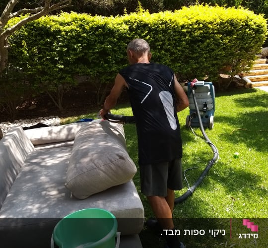 אדם מנקה ספה עם מכונת ניקוי חיצונית